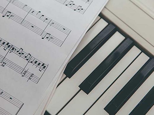 Das Bild zeigt eine Klaviertastatur mit Notenblatt