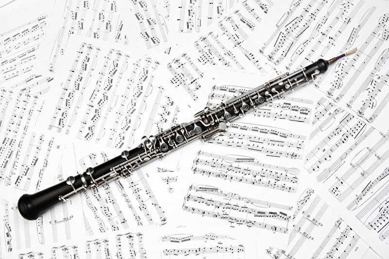 Das Bild zeigt eine Oboe auf vielen Notenblättern liegend.