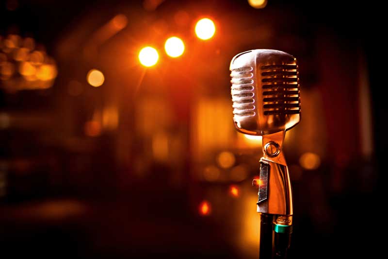 Dieses Bild zeigt ein Mikrofon welches auf einer Bühne steht.