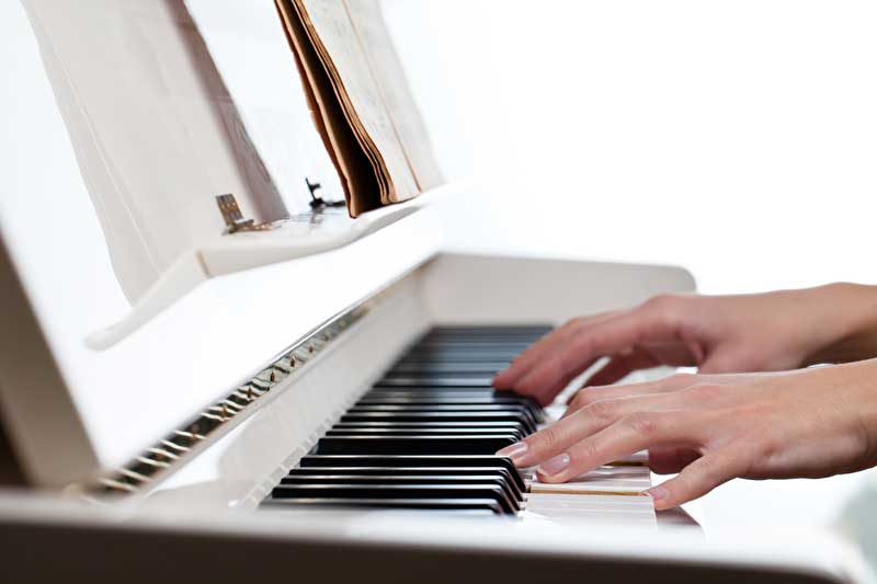 Das Bild zeigt Hände welche auf einem Klavier spielen.